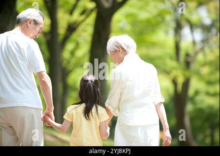 Una coppia anziana che cammina con i nipoti nel parco Foto Stock