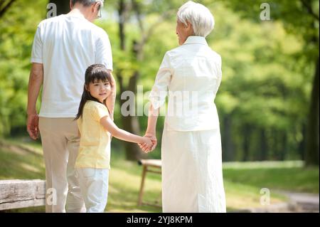 Una coppia anziana che cammina con i nipoti nel parco Foto Stock