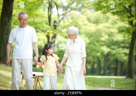 Una coppia anziana che cammina con i nipoti nel parco Foto Stock