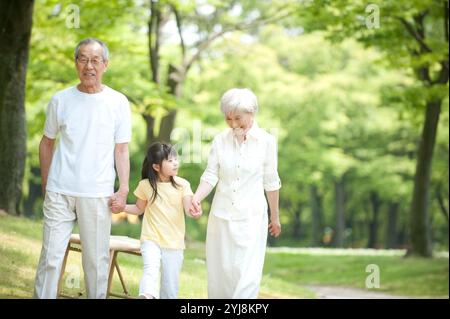 Una coppia anziana che cammina con i nipoti nel parco Foto Stock