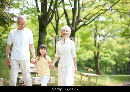 Una coppia anziana che cammina con i nipoti nel parco Foto Stock