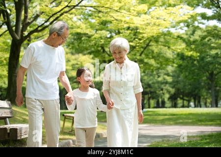 Coppia di anziani e nipoti che camminano nel parco Foto Stock