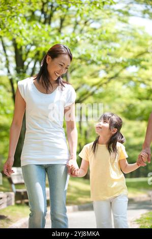 Una famiglia di tre persone che fa una passeggiata nel parco Foto Stock