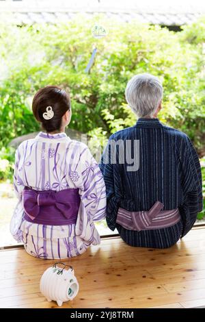 Coppia di mezza età in yukata sulla veranda, vista posteriore Foto Stock