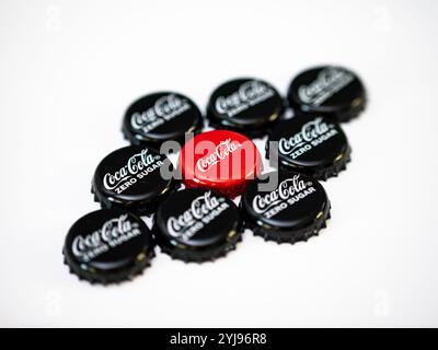 Tappi per bottiglie Coca Cola su sfondo bianco. Diversi prodotti di coca come il gusto originale e lo zucchero zero. Il cappuccio rosso è al centro. Foto Stock