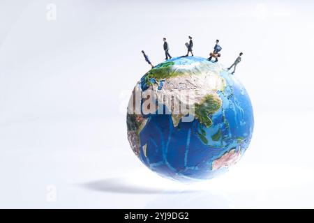 Bambole in miniatura che viaggiano per il mondo con un modello della Terra Foto Stock