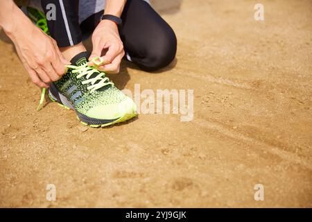 Sportivo che lega i lacci delle scarpe sul campo da gioco Foto Stock