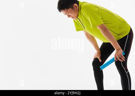 Un atleta maschile in pista e sul campo in ginocchio, stanco dopo aver eseguito la staffetta Foto Stock