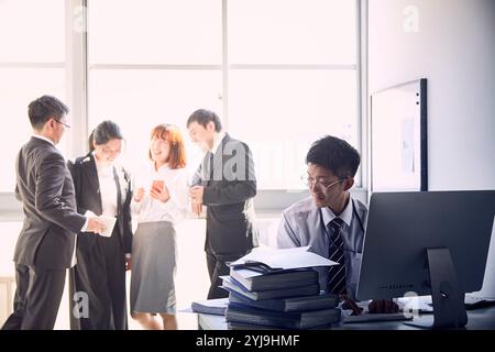 I giovani dipendenti lavorano molto da soli e i loro capi si divertono senza lavoro Foto Stock