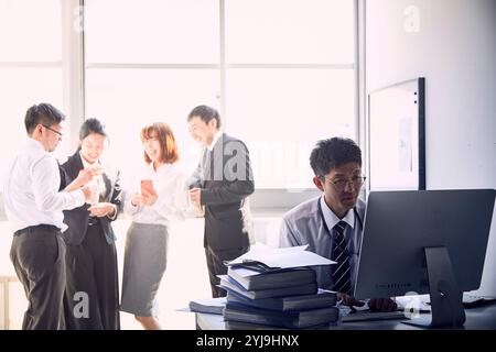 I giovani dipendenti lavorano molto da soli e i loro capi si divertono senza lavoro Foto Stock