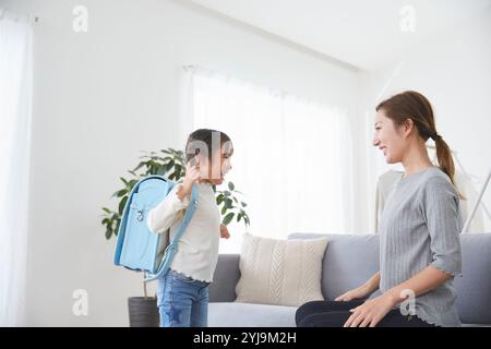 Bambino e madre si preparano per la scuola in salotto Foto Stock