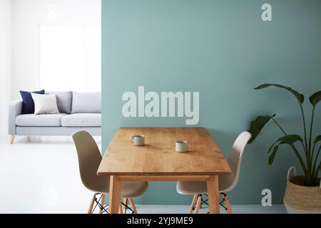 Sala da pranzo davanti a una parete verde con divano grigio sul retro Foto Stock