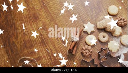 Immagine di stelle che cadono sopra i biscotti di natale sul tavolo. Natale e festeggiamenti, immagine generata digitalmente. Foto Stock