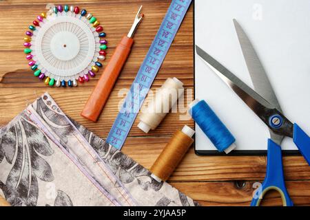 Colorate forniture di cucito disposte intorno a un portadocumenti vuoto su un tavolo di legno Foto Stock