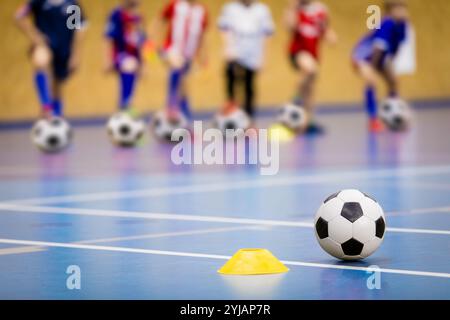 Allenamento di calcio al coperto per bambini. Gruppo di bambini con palle da calcio in classe di educazione fisica Foto Stock