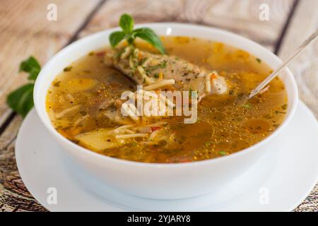 zuppa di pollo e spaghetti cotti a caldo in un piatto su un tavolo di legno. Foto Stock