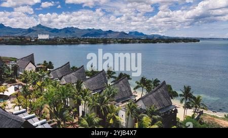 Una fotografia aerea che cattura la bellezza panoramica di un'isola tropicale con palme e montagne sullo sfondo. Foto Stock