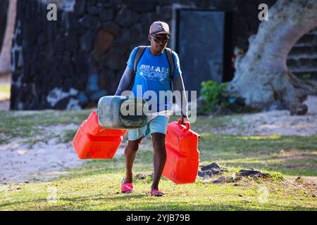 Un ritratto di un uomo del posto a Mauritius che porta tre secchi arancioni sulla schiena. Foto Stock