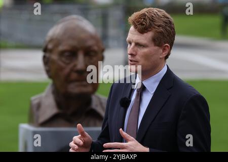 L'inviato speciale uscente degli Stati Uniti per l'Irlanda del Nord Joesph Kennedy, si trova di fronte al busto del senatore statunitense George J. Mitchell e dell'ex cancelliere della Queen's University, mentre parla ai media al di fuori del Global Innovation Summit 2024, nella Whitla Hall della Queen's University di Belfast. Data foto: Giovedì 14 novembre 2024. Foto Stock