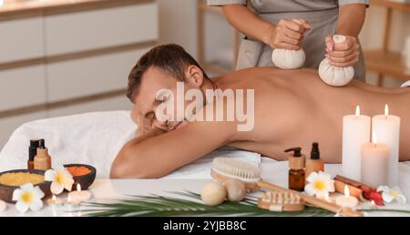 Giovane che riceve un massaggio con sacchetti di erbe nel salone termale Foto Stock