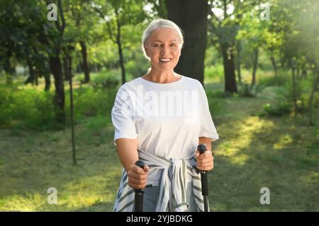 Donna matura con pali da passeggio nel parco, primo piano Foto Stock