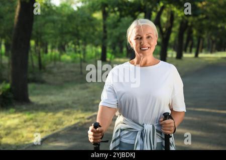 Donna matura con pali da passeggio nel parco, primo piano Foto Stock