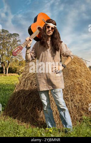 Ritratto di un uomo hippie di mezza età dai capelli lunghi con una chitarra Foto Stock