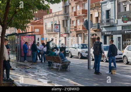 Viladecans. Spagna - 14 novembre 2024: Fermata dell'autobus trafficata a Viladecans, con molte persone in attesa dell'autobus. La scena riflette la vita quotidiana urbana e la Foto Stock