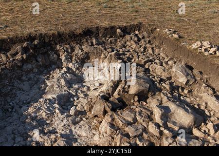 Luogo di lavoro degli archeologi. Fondo roccioso di una fossa archeologica scavata su una collina alla ricerca di manufatti storici Foto Stock