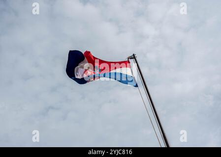 Bandiera croata che sventola nel vento contro un cielo blu brillante, simboleggiando l'orgoglio nazionale e il patriottismo. Foto Stock