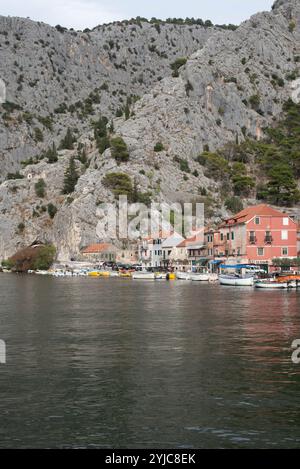 Vista della città di Omis dal fiume Cetina, in Croazia, con il fiume panoramico che scorre attraverso la valle, circondato da aspre montagne e dal carpino della città Foto Stock