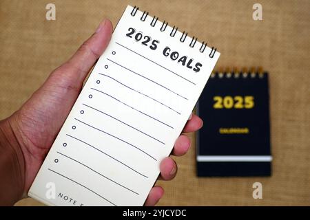 Tenere a mano una lista di controllo per 2025 goal con calendario 2025. Obiettivi, risoluzioni, piano, azione, concetto di checklist per il nuovo anno 2025. Il risoluta' dell'anno nuovo Foto Stock