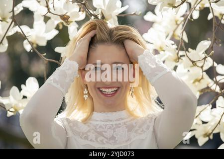 Giovane donna, bionda, ritratto, Risate, boschetto di magnolia, davanti alla magnolia in fiore, magnolias, Stoccarda, Baden-Wuerttemberg, Germania, Europa Foto Stock
