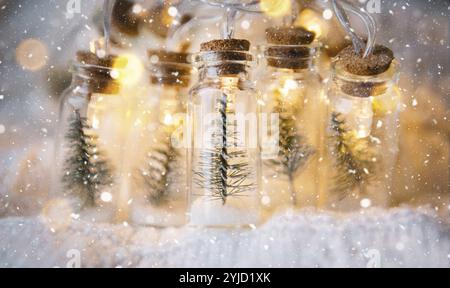 Fata luci in un vaso con un albero di Natale e la neve primo piano su un ambiente caldo e accogliente con ghirlanda d'oro. Natale e Capodanno, arredamento festivo, fotocopiatrice spa Foto Stock