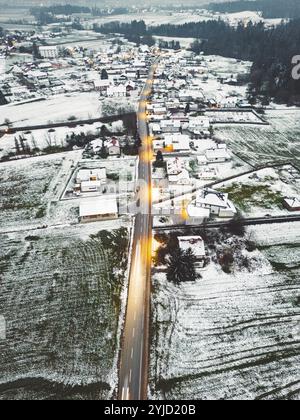 Vista aerea della comunità suburbana in inverno la sera. Neve sul terreno, buio, luci stradali brillanti Foto Stock