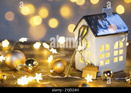 Chiave per la casa con un portachiavi su una lampada con un arredamento di Natale. Un regalo per Capodanno, Natale. Costruzione, progettazione, progetto, trasferimento a casa nuova, mor Foto Stock