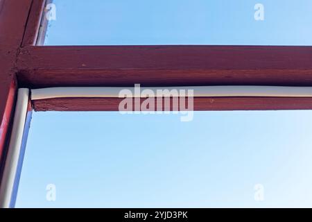 Nastro isolante fissato a un vecchio telaio in legno per finestre per sigillare e resistere alle intemperie, mostra un primo piano dei lavori di ristrutturazione di abitazioni fai da te. Il concetto di casa repa Foto Stock