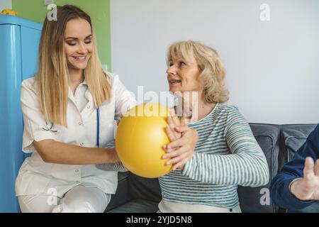 Giovane donna bionda che si occupa di aiutare una donna anziana a casa. Infermiera che assiste la sua paziente anziana a casa di riposo. Donna anziana aiutata dall'infermiera A. Foto Stock