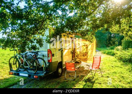 Ein camper mit Fahrrädern auf einem Heckträger steht in idylischer Umgebung im Sommer auf einer Wiese zwischen Bäumen, Vogesen, Frankreich. MIT einem Campervan unterwegs *** Un camper con biciclette su un portapacchi posteriore si erge in un ambiente idilliaco in estate su un prato tra alberi, Vosgi, Francia che viaggia con un camper Foto Stock