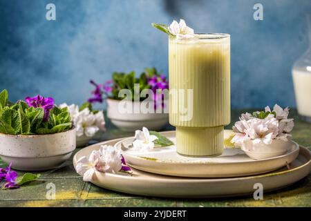 Rinfrescante latte matcha freddo guarnito con delicati fiori e foglie di menta, creando una bevanda visivamente attraente e saporita Foto Stock