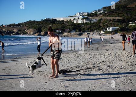 uomo che dondola un cane su una corda a camp bay clifton, sudafrica Foto Stock