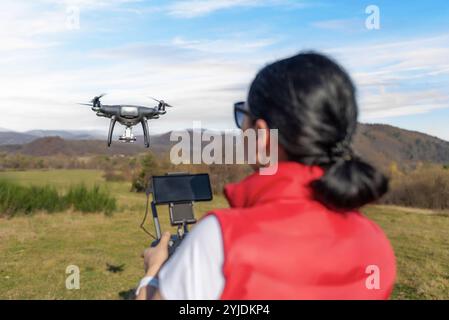 Una giovane donna controlla un drone. Foto Stock