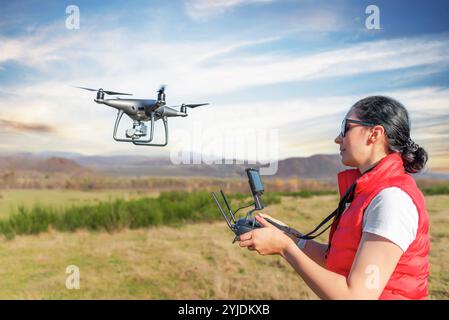 Una giovane donna controlla un drone. Foto Stock