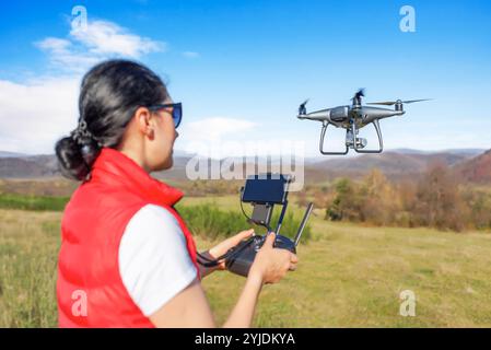 Una giovane donna controlla un drone. Foto Stock