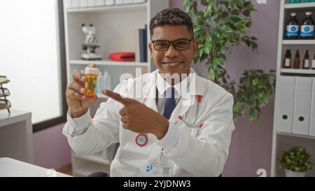 Medico sorridente che indica una bottiglia di prescrizione in una stanza clinica illuminata con scaffali e attrezzature mediche Foto Stock