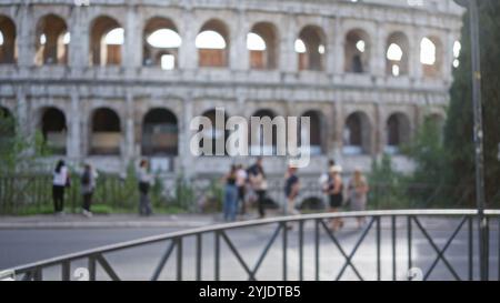 Scena sfocata di persone che passeggiano vicino all'iconico colosseo di roma, in italia, che mostra un effetto bokeh defocalizzato che mette in risalto l'architetto storico Foto Stock