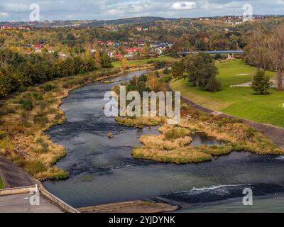 Un pittoresco fiume che si snoda attraverso un lussureggiante paesaggio autunnale con vegetazione vivace e case pittoresche Foto Stock