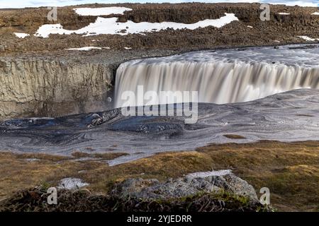 Cascata Dettifoss nel Parco Nazionale di Vatnajokull nel nord-est dell'Islanda, vista panoramica del canyon con colonne basaltiche, ghiaccio e neve, lunga esposizione. Foto Stock