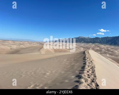Impronte su dune di sabbia con montagne sullo sfondo Foto Stock