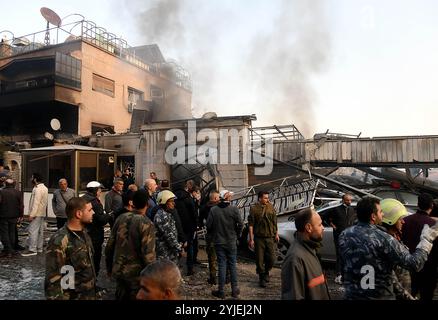 Damasco, Siria. 14 novembre 2024. La gente si riunisce di fronte a un edificio residenziale distrutto negli attacchi aerei israeliani nel quartiere Mazzeh di Damasco, in Siria, il 14 novembre 2024. Le forze israeliane hanno condotto giovedì attacchi aerei su edifici residenziali nella capitale siriana Damasco e nelle sue vicinanze, uccidendo almeno 15 persone e ferendone altre 16, secondo il Ministero della difesa siriano e la TV di stato. Crediti: Ammar Safarjalani/Xinhua/Alamy Live News Foto Stock